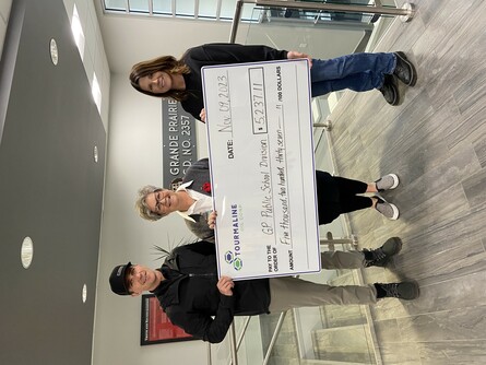 Three people holding up a big cheque